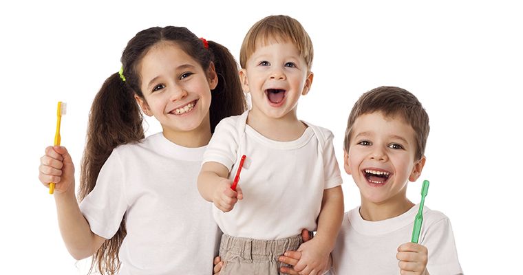 Three kids holding up their toothbrushes wondering if they should start orthodontic treatment.